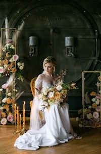a bride sitting on a chair with a bouquet of flowers