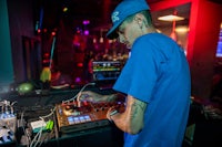 a man in a blue hat is djing at a night club