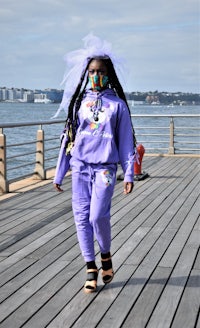 a woman wearing purple dreadlocks walking on a pier