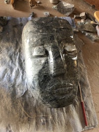 a large stone head is sitting on top of a piece of cloth