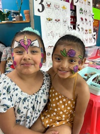 two girls posing for a photo at a face painting event