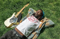 a man laying on the grass with a guitar