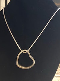 a silver heart shaped necklace on a mannequin