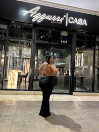 a woman in a black dress standing in front of a store