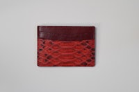 a red python skin card holder on a white surface