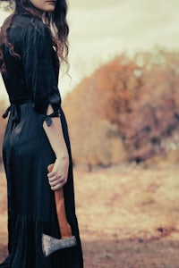 a woman in a black dress holding an axe