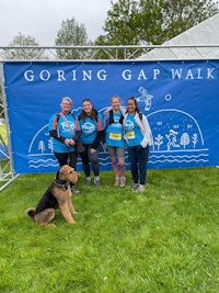 a group of people and a dog posing in front of a banner that says going gap walk