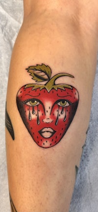 a strawberry tattoo on a woman's thigh