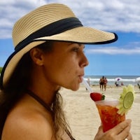 a woman in a straw hat drinking a drink on the beach