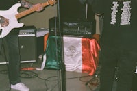 a man playing a guitar in a room with a mexican flag