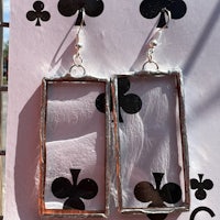 a pair of silver earrings with playing cards on them