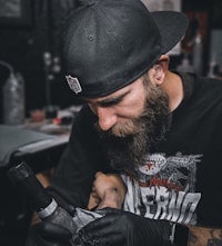 a man with a beard is getting a tattoo