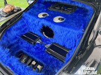 a blue furry monster in the trunk of a car
