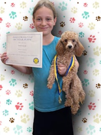 a girl with a poodle holding a certificate