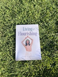 a woman laying on the grass with a book in her hands