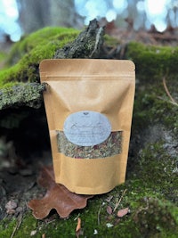 a bag of herbal tea sitting on top of moss in the woods