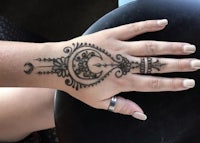 a woman's hand with a henna tattoo on it