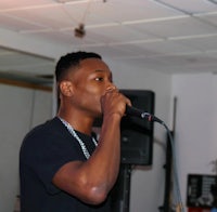 a man in a black shirt is singing into a microphone