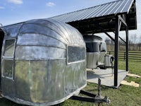 a silver airstream trailer is parked in a field