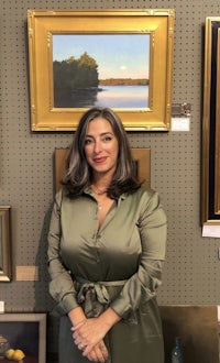 a woman standing in front of framed paintings