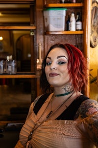 a woman with red hair and tattoos standing in front of a bar
