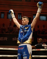 a boxer raises his fist in the air in a boxing ring