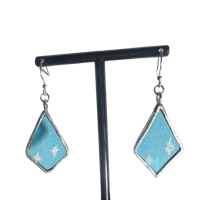 a pair of blue and white earrings on a metal stand