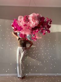 a woman standing in front of a pink flower cloud
