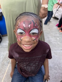 a little boy with a spider man face painted on his face