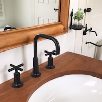 a bathroom sink with a black faucet and mirror