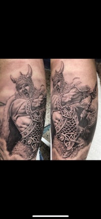 a tattoo of a viking with horns on his thigh