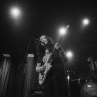 a black and white photo of a woman playing a guitar