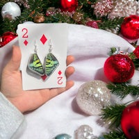a person holding a playing card in front of christmas decorations