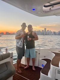two men standing on the deck of a boat at sunset