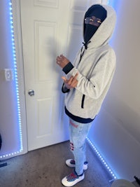 a man in a gray hoodie standing in front of a door