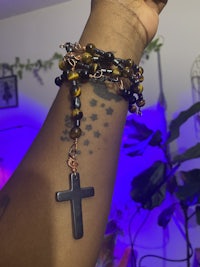 a woman wearing a tiger eye rosary with a cross on it