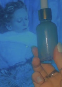 a person holding a bottle of liquid in front of a blue screen