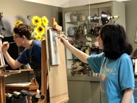 two women working in an art studio with sunflowers
