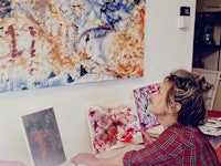 a woman sitting at a desk in front of a painting