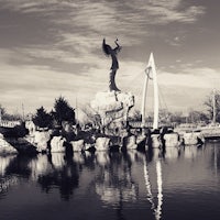 a black and white photo of a statue in the water