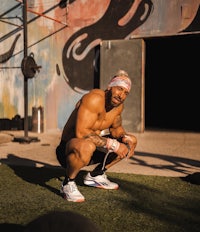 a man squatting in front of a wall