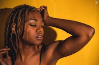 a woman with dreadlocks posing against a yellow background