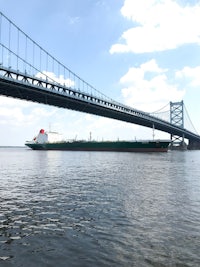 a large cargo ship is passing under a bridge