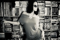 a woman posing in front of a book shelf