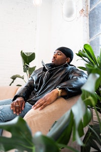 a man in a leather jacket sitting on a couch