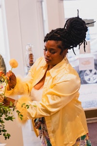 a woman with dreadlocks arranging flowers in a vase