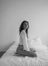 a woman in white lingerie sitting on a bed