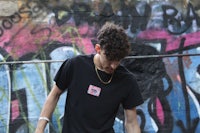 a young man wearing a black t - shirt with graffiti on it