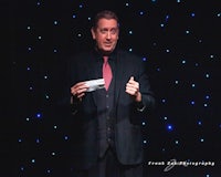 a man in a suit is holding up a piece of paper