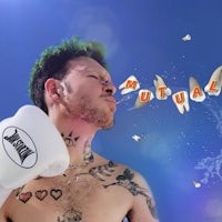a man with tattoos and a boxing glove blowing bubbles